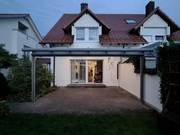 Terrassenüberdachung aus Aluminium an Einfamilienhaus bei Dämmerung