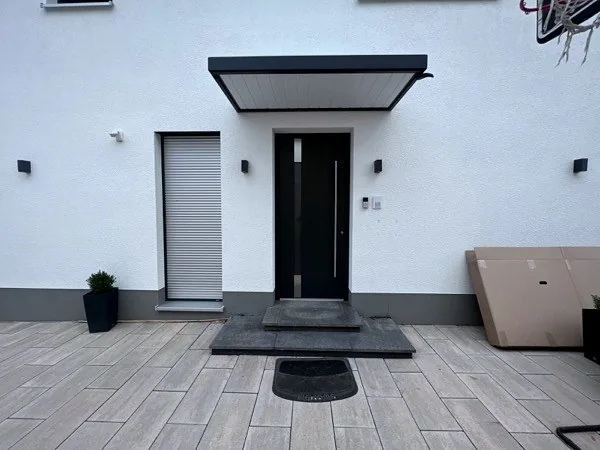 Anthrazitfarbene Haustür mit Vordach und Rollladen am Eingangsbereich